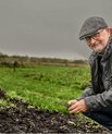 Professor Mogens H. Greve står med hænderne i jorden