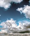 [Translate to English:] Foto af hvide og grå skyer på en blå himmel.