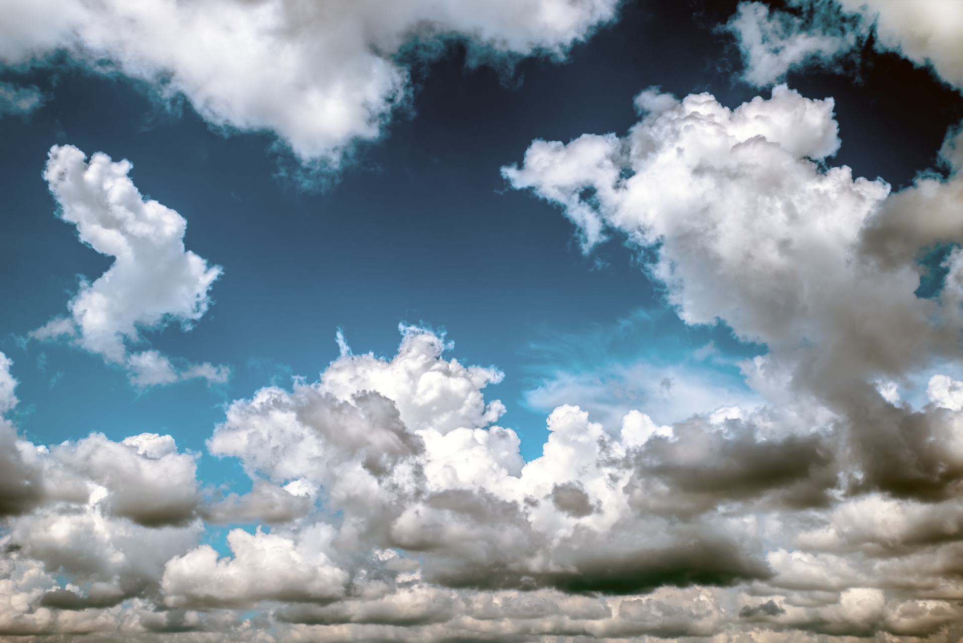 [Translate to English:] Foto af hvide og grå skyer på en blå himmel.